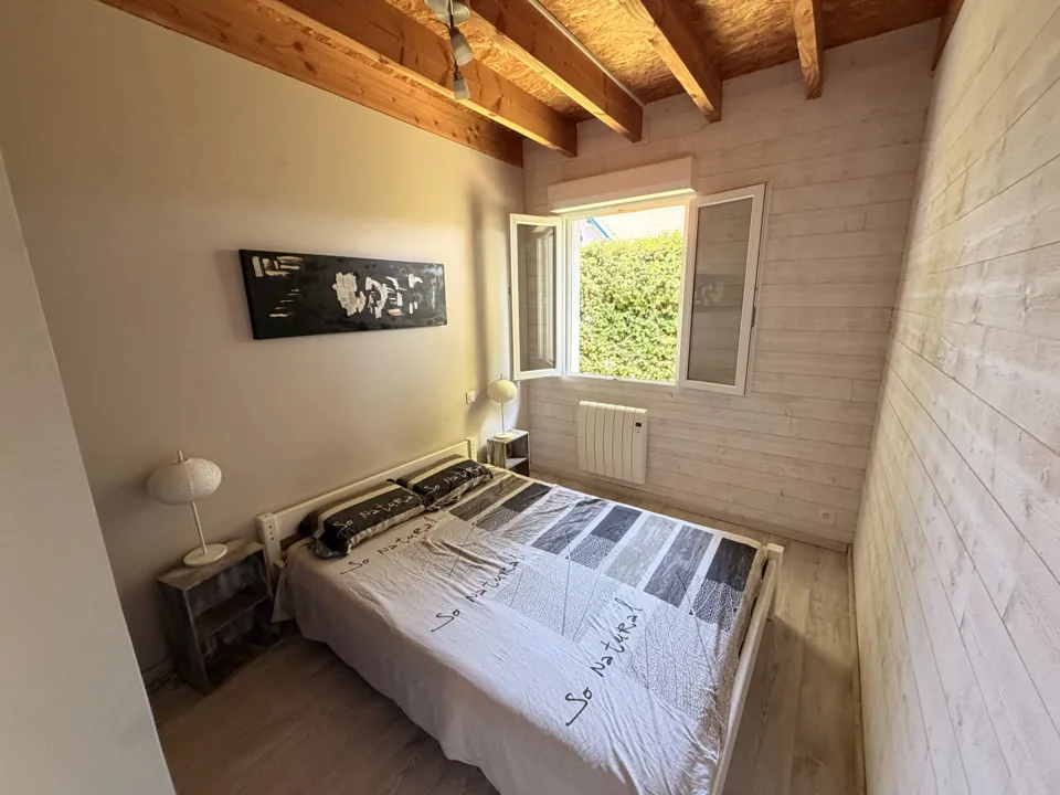 Chambre double lumineuse avec fenêtre ouverte et plafond à poutres apparentes
